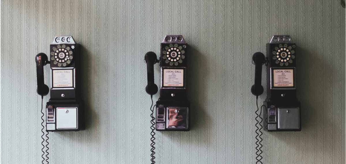 3 vintage phones hanging on wall