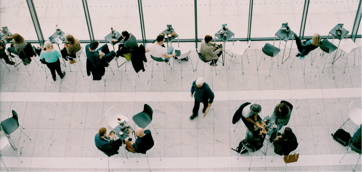 Large space filled with small tables, people talking and eating.